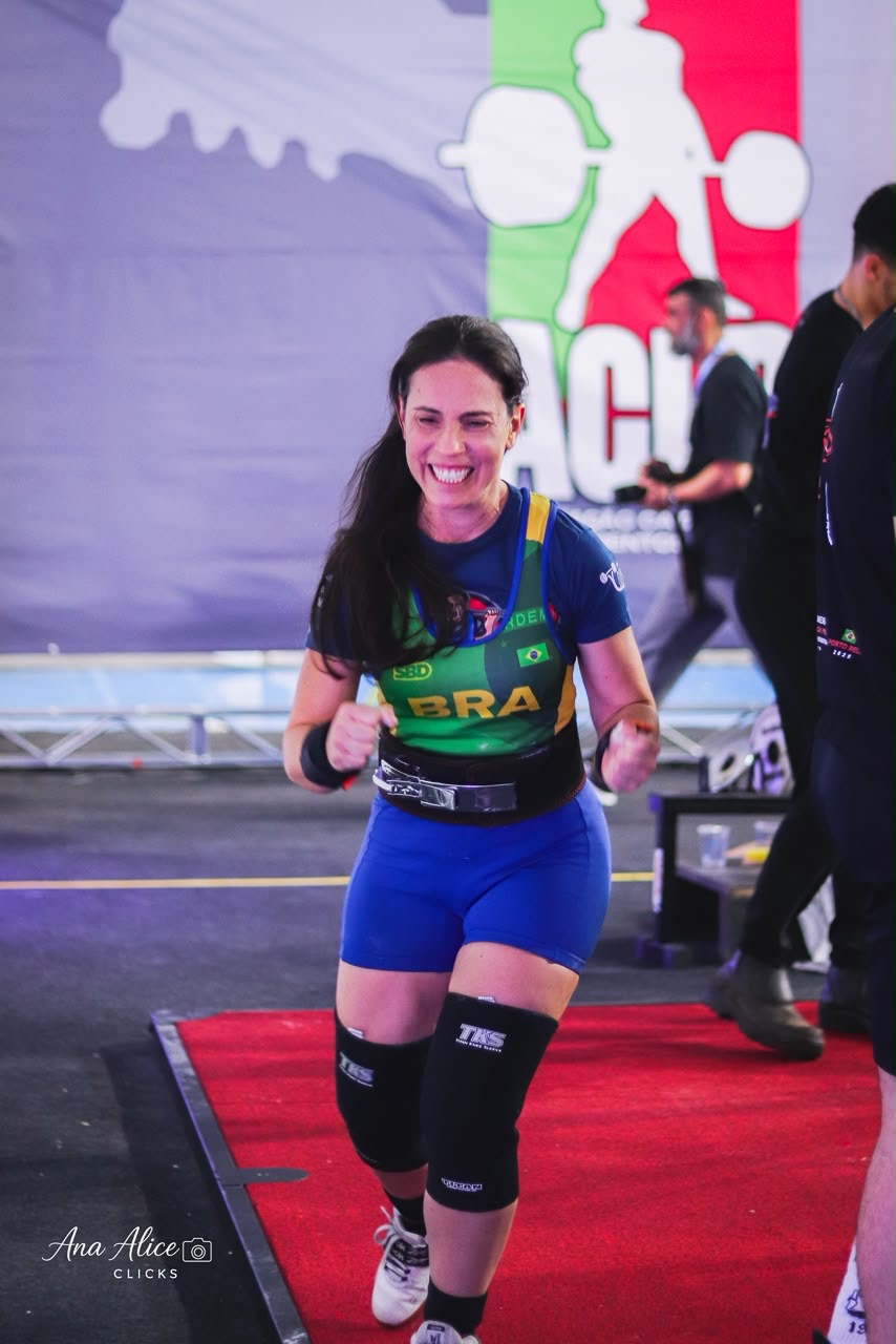 Érica Duque sorrindo na plataforma de competição com o uniforme do Brasil